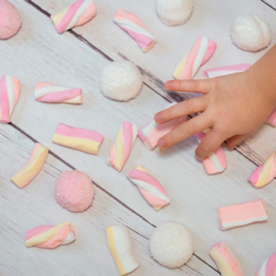 Bilde av armen til et barn som er i ferd med å plukke opp godteri fra et gulv.