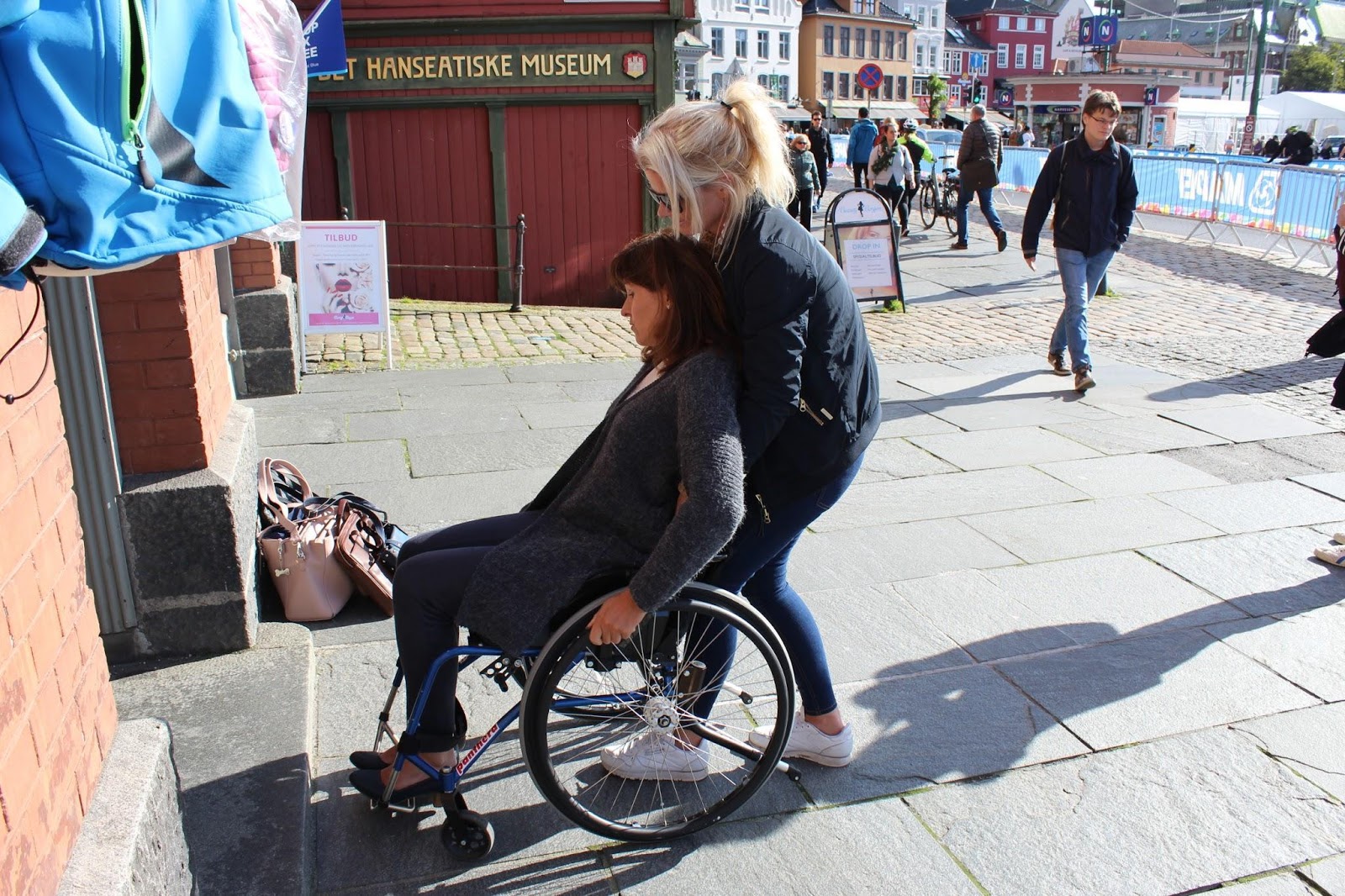 Bilde av Bergens varaordfører Marita Moltu i rullestol som får assistanse inn i en bygning av en assistent fra Prima Assistanse.