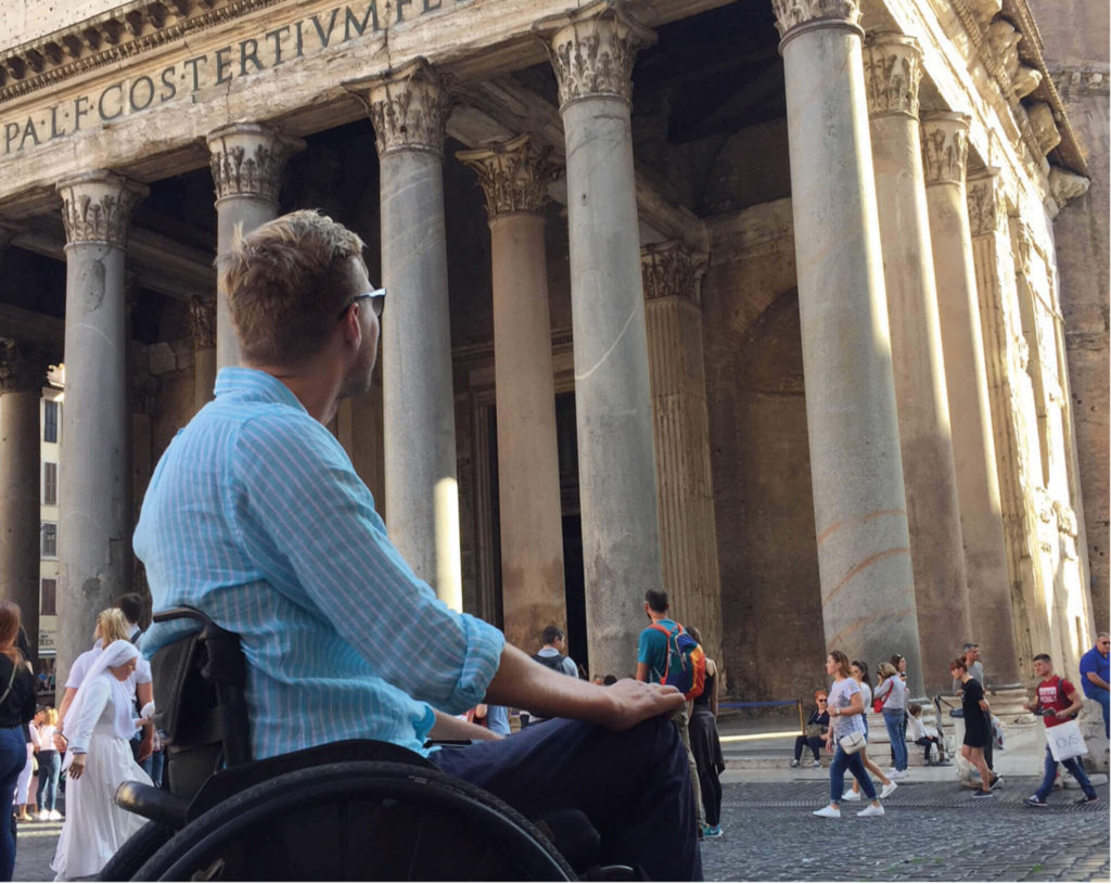 Bilde av BPA-konsulent Lars Ivar Eilerås i rullestol iført en blå-stripete skjorte. Han kikker opp mot det historiske bygget Pantheon i Roma.