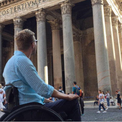 Bilde av BPA-konsulent Lars Ivar Eilerås i rullestol iført en blå-stripete skjorte. Han kikker opp mot det historiske bygget Pantheon i Roma.