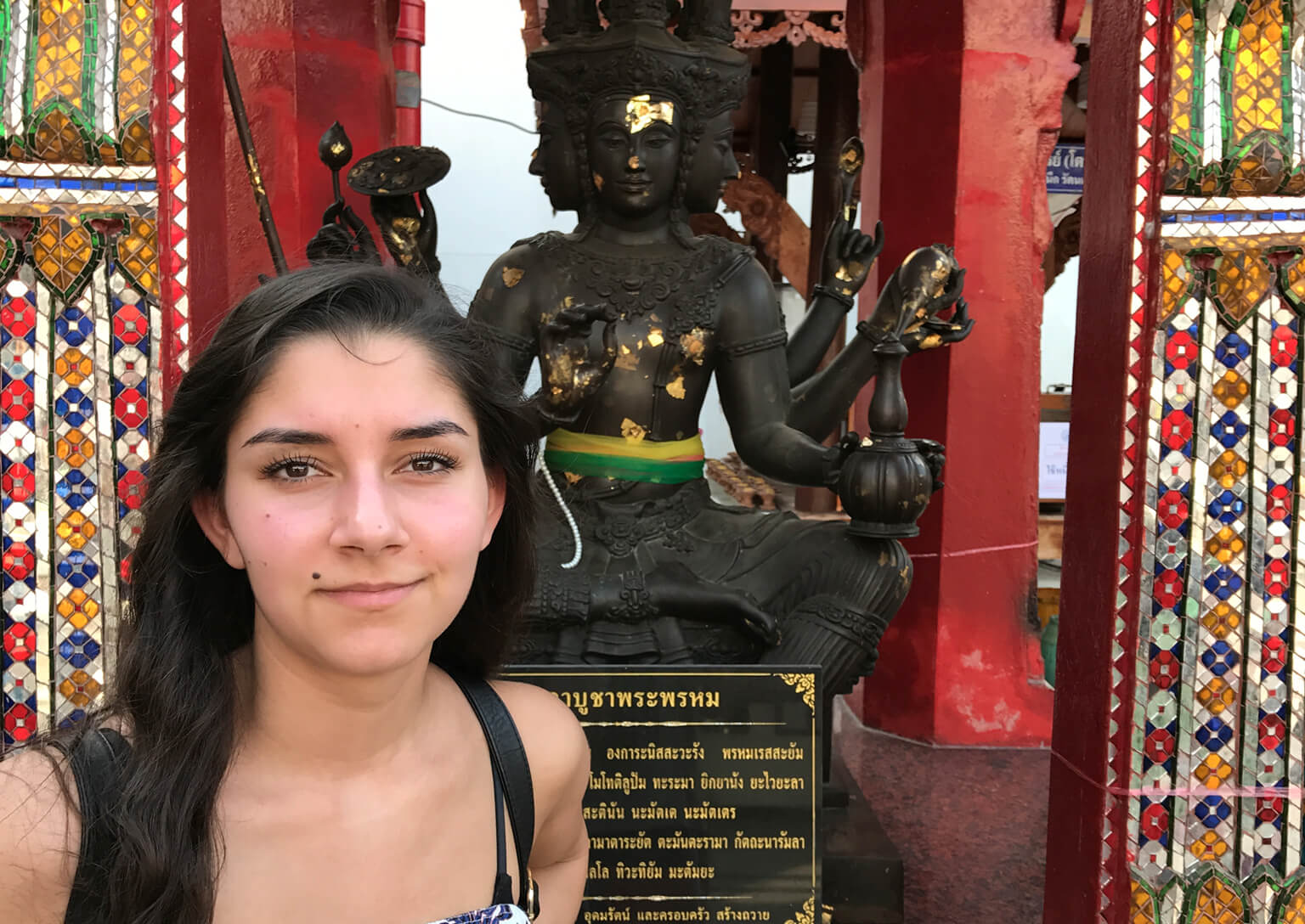 Bilde av artikkelskribent Noor som står foran en hinduistisk statue. Hun kikker rett inn i kameraet