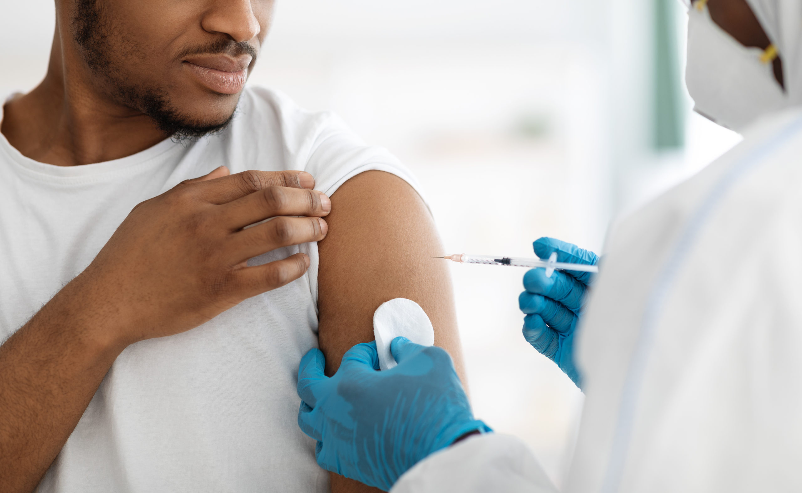 Mann mottar vaksine av en lege med hansker