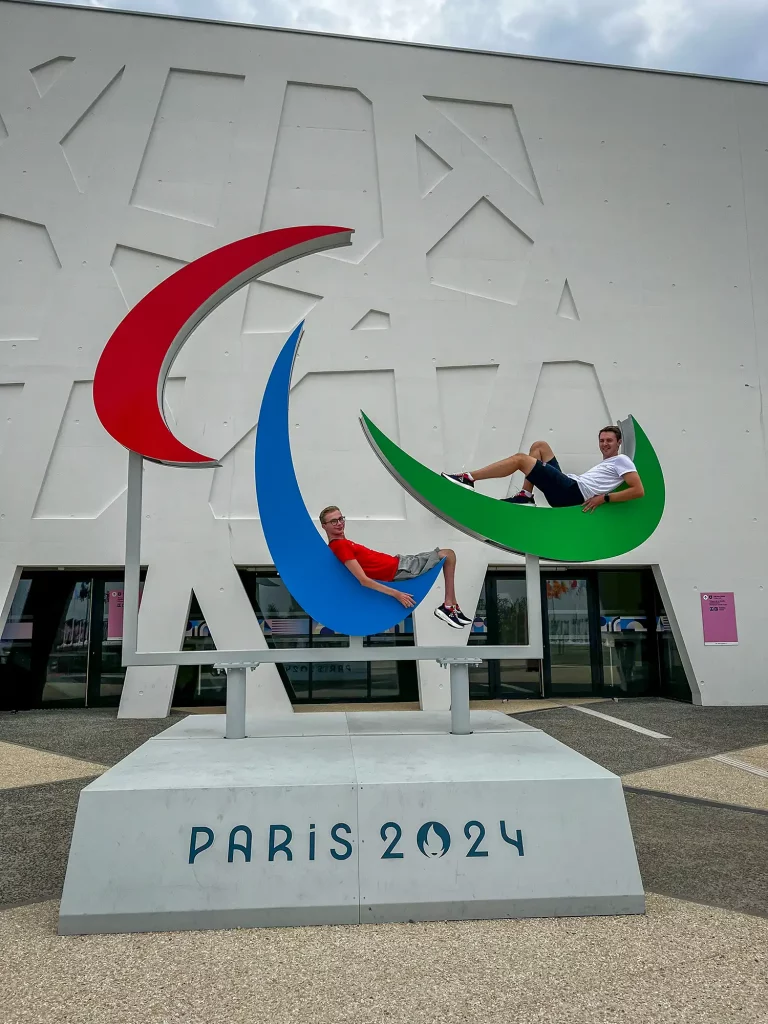 Martin og assistent ligger oppå Paralympics Paris 2024- statuen. 