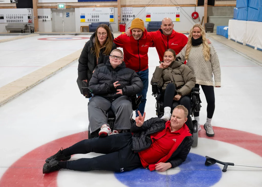 syv personer som smiler mot kamera på curlingbanen til Skien Fritidspark