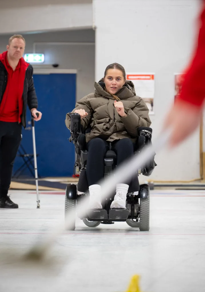 jente i rullestol som spiller curling på isbane