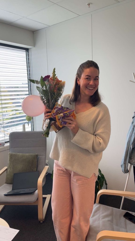 dame som smiler og holder oppe en blomsterbukett