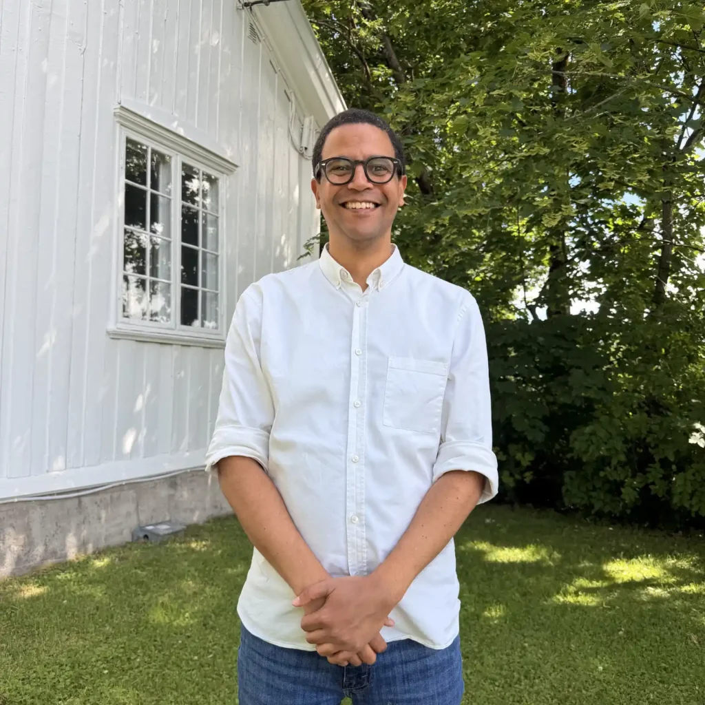 mann som smiler mot kamera på en gressplen foran et hus